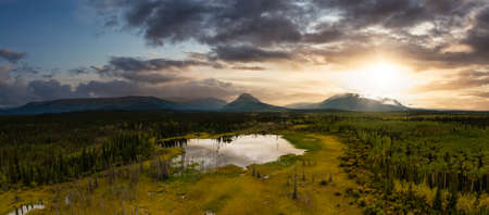 Peaceful Panoramic View of Pond and Marshland, surrounded by Forest and Mountains in Canadian Nature. Sunset Sky. Aerial Drone Shot. West of Whitehorse, East of Haines Junction, Yukon, Canada.の写真素材