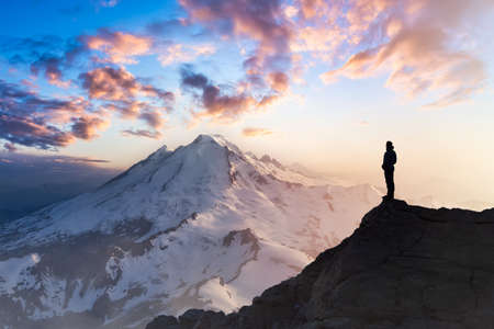 Adventure, Explore and Lifestyle Concept Composite. Adventurous Man Hiker on top of a Steep Rocky Cliff. Sunset or Sunrise. Landscape Taken from Washington, USA.の写真素材