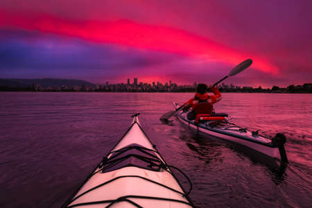 Kayaking in the ocean with modern city and mountains in background. Sunrise Colorful Sky Art Render. Taken in Jericho, Vancouver, British Columbia, Canada. Concept: Adventure, Lifestyle, Sportの写真素材