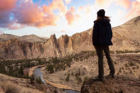 Man enjoying the Beautiful American Mountain Landscape. Dramatic Sunrise Sky Art Render. Taken in Smith Rock, Redmond, Oregon, America. Concept: Adventure, Holiday and Travelの写真素材