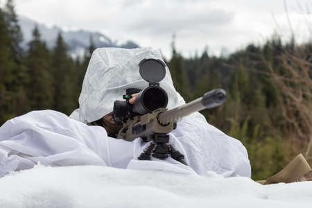 Army Man wearing Tactical Uniform with Sniper River Camouflaged in Snow Aiming at the Target. Winter...