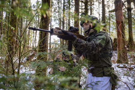 Army Man wearing Tactical Uniform and holding Machine gun in the Outdoor Rain Forest. Winter...
