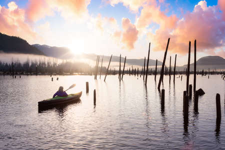 Adventurous Girl kayaking on an infatable kayak in a beautiful lake. Colorful peaceful Sunrise Art Render. Taken in Stave Lake, East of Vancouver, British Columbia, Canada. Adventure and vacationの写真素材