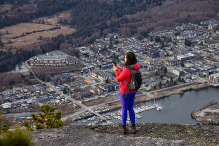 Adventurous Female Hiker on top of Chief Mountain taking pictures of a beautiful view from above of...