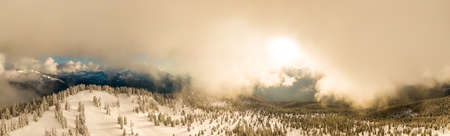 Aerial Panoramic View of Canadian Nature Landscape on top of snow covered mountain and green trees...