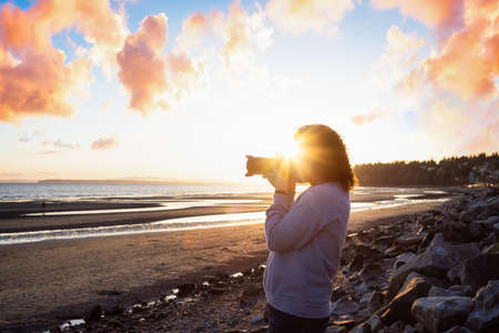 Adventure Travel Photographer at West Pacific Ocean Coast. Colorful Sunny Sunset. Adult White...