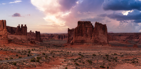 Panoramic landscape view of a Scenic road in the red rock canyons. Dramatic Colorful Sunset Sky Artistic Render. Taken in Arches National Park, located near Moab, Utah, United States.の写真素材