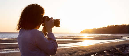 Adventure Travel Photographer at West Pacific Ocean Coast. Colorful Sunny Sunset. Adult White Caucasian Woman. Location: White Rock, Greater Vancouver, BC, Canada.の写真素材