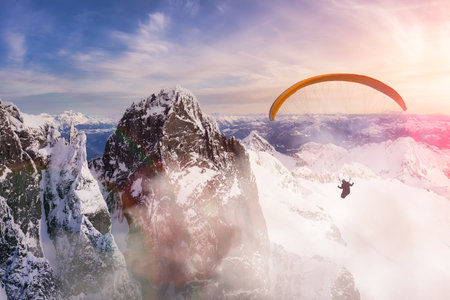 Adventure Composite Image of Paraglider Flying up high in the Rocky Mountains. Sunny Sunset Sky....