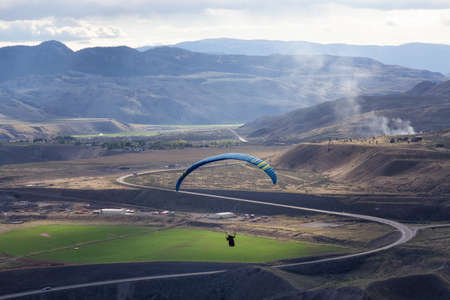 Savona, British Columbia, Canada - May 8, 2021: Adventurous Man Flying on a Paraglider around the...