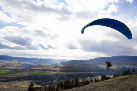 Savona, British Columbia, Canada - May 8, 2021: Adventurous Man Flying on a Paraglider around the mountains.のeditorial素材