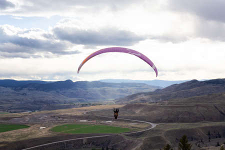 Savona, British Columbia, Canada - May 8, 2021: Adventurous Man Flying on a Paraglider around the...