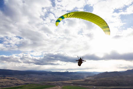 Savona, British Columbia, Canada - May 8, 2021: Adventurous Woman Flying on a Paraglider around the mountains.のeditorial素材