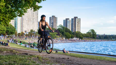 Adventurous White Caucasian Adult Woman riding a road bicycle in Stanley Park in a modern city....