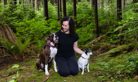 White Caucasian Adult Woman playing with Dogs in the Canadian Forest. Golden Ears Provincial Park,...