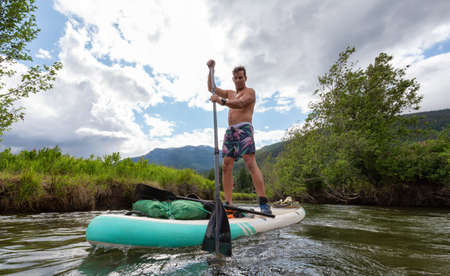Adventurous Hispanic Adult Athletic Man paddle boarding on The River of Golden Dreams. Located in Whistler, British Columbia, Canada.の写真素材