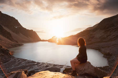 Adventurous Caucasian Adult Woman Hiker on top of a Canadian Rocky Mountain. Sunny Summer Sunset Art...