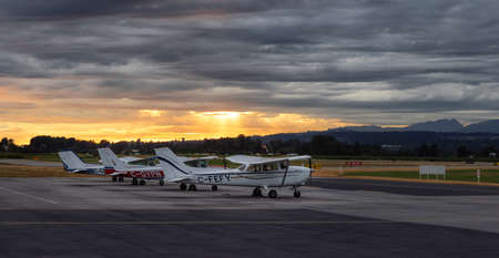 Pitt Meadows, Greater Vancouver, British Columbia, Canada - August 5, 2021: Airplanes parked at the Airport Apron during a dramatic cloudy sunset.のeditorial素材
