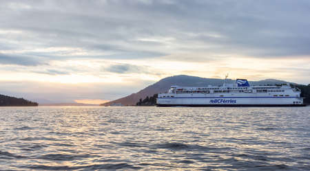 Victoria, Vancouver Island, British Columbia, Canada - August 20, 2021: BC Ferries Boat arriving at the Terminal in Swartz Bay during cloudy summer sunset.のeditorial素材