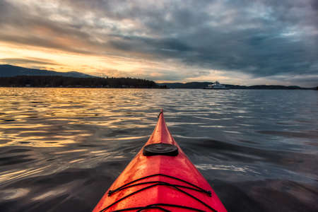 Sea Kayak paddling in the Pacific Ocean. Dramatic Sunset Sky. Taken near Victoria, Vancouver Islands, British Columbia, Canada. Concept: Sport, Adventureの写真素材