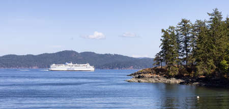Salt Spring Island, British Columbia, Canada - August 23, 2021: BC Ferries passing by the rocky shores of Gulf Islands during a sunny summer day.のeditorial素材