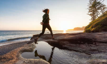 Adventurous White Caucasian Woman at Sandcut Beach on the West Coast of Pacific Ocean. Summer Sunny Sunset. Canadian Nature. Located near Victoria, Vancouver Island, BC, Canada.の写真素材