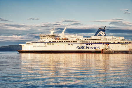 Victoria, Vancouver Island, British Columbia, Canada - August 26, 2021: BC Ferries Boat at the Terminal in Swartz Bay during cloudy summer sunset.のeditorial素材