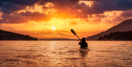Adventurous Woman on Sea Kayak paddling in the Pacific Ocean. Dramatic Sunset Sky Art Render. Taken near Victoria, Vancouver Islands, British Columbia, Canada. Concept: Sport, Adventureの写真素材