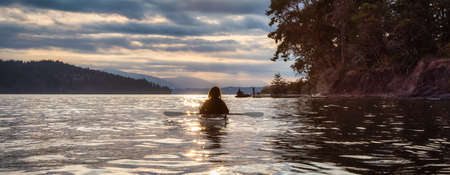 Adventurous Woman on Sea Kayak paddling in the Pacific Ocean. Summer Sunset Sky. Taken near Victoria, Vancouver Islands, British Columbia, Canada. Concept: Sport, Adventureの写真素材