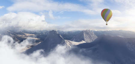 Dramatic Mountain Landscape covered in clouds and Hot Air Balloon Flying. 3d Rendering Adventure Dream Concept Artwork. Aerial Image from British Columbia, Canada. Cloudy Skyの写真素材