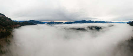 Aerial Panoramic View of Canadian Mountain Landscape covered in fog over Harrison Lake. Winter...