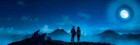 Magical Night Scene with Adult Man and Woman holding hands at Rocky Mountain Nature with Big Full Moon. Adventure Art 3d Rendering shore. Background Landscape from Alaska. Love, Relationship Conceptの写真素材