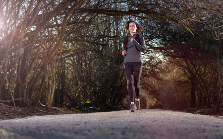 White Caucasian Adult Woman Running on a trail in a Rain Forest. Taken in Surrey, Vancouver, British...