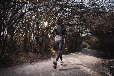 Athletic Caucasian Adult Woman Running on a trail in a Rain Forest. Taken in Surrey, Vancouver,...