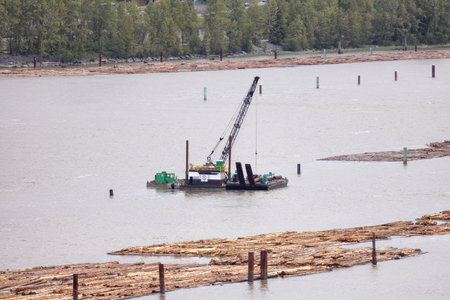Surrey, Vancouver, BC, Canada - May 19, 2022: Aerial View of Industrial Site, Crane, and Logs on Fraser River.のeditorial素材