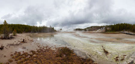 Hot spring Geyser with colorful water in American Landscape. Cloudy Sky. Yellowstone National Park,...