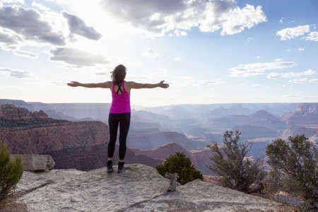 Adventurous Traveler standing on Desert Rocky Mountain American Landscape. Cloudy Sunny Sky. Grand...
