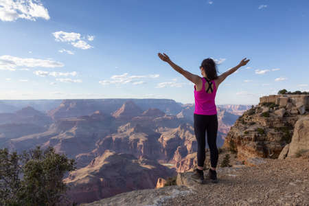 Adventurous Traveler standing on Desert Rocky Mountain American Landscape. Cloudy Sunny Sky. Grand...
