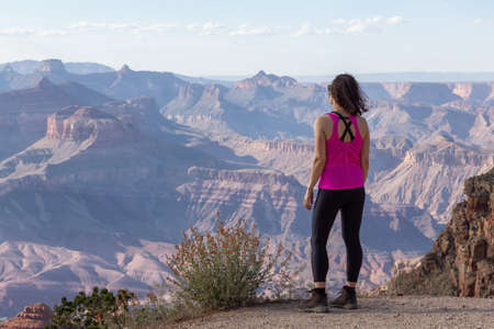 Adventurous Traveler standing on Desert Rocky Mountain American Landscape. Cloudy Sunny Sky. Grand...