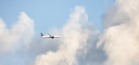 Vancouver, British Columbia, Canada - June 16, 2022: Air Canada Jet Airplane Flying in the Sky near puffy clouds.のeditorial素材