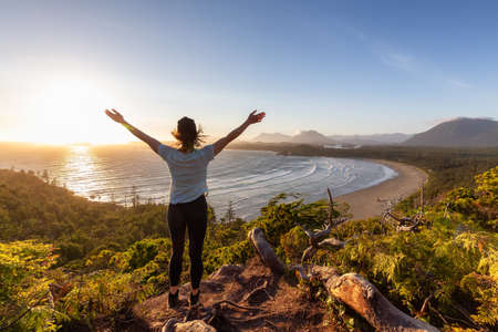Adventurous Woman Hiker overlooking Sandy Beach on the West Coast of Pacific Ocean. Canadian Nature Landscape Background. Cox Bay Lookout, Tofino, Vancouver Island, BC, Canada.の写真素材