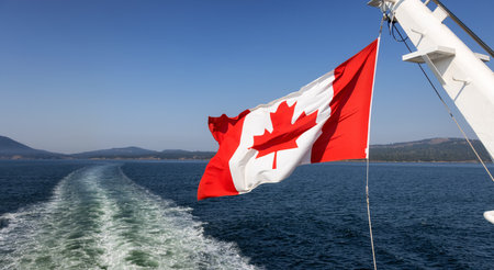 Canadian National Flag on a back of a ship traveling near Vancouver Island, British Columbia, Canada. Adventure Travel Concept.の写真素材
