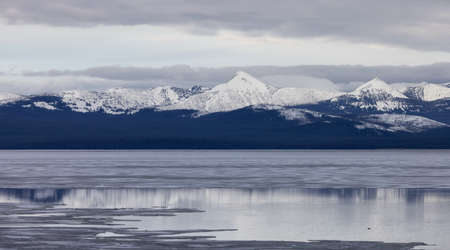 View of a frozen Yellowstone Lake with snow covered mountains in American Landscape. Yellowstone...