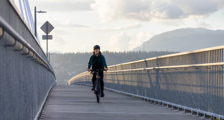Caucasian Woman riding on a bicycle on a bike lane at Port Mann Bridge. Greater Vancouver, British Columbia, Canada.の写真素材