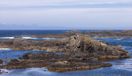 Rugged Rocks on a rocky shore on the West Coast of Pacific Ocean. Summer Morning Sky. Ucluelet,...