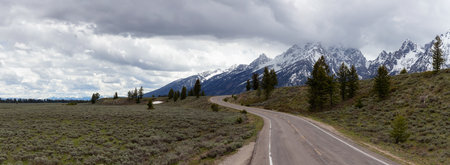 Scenic Road surrounded by Mountains in American Landscape. Spring Season. Grand Teton National Park. Wyoming, United States. Nature Background Panoramaの写真素材