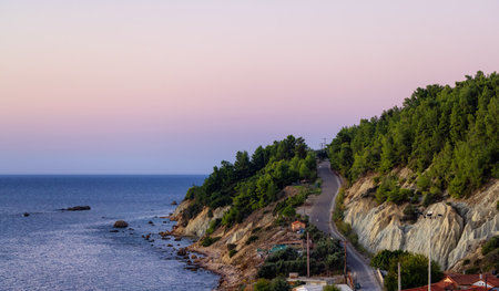 Scenic Road by the Rocky Coast on Ionian Sea in a small touristic Town. Katakolo, Greece. Twilight Sunrise Sky.の写真素材