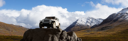 Yukon, Canada - August 31, 2020: Jeep on top of rocks with mountain landscape in background. 3d Rendering Vehicle Composition.のeditorial素材