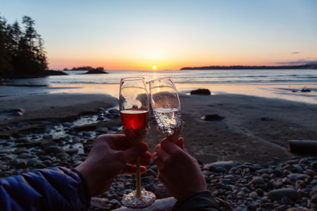 Man and Woman Cheers with Champagne Flute Glasses on the Beach at Sunset. Tofino, Vancouver Island, British Columbia, Canada.の写真素材