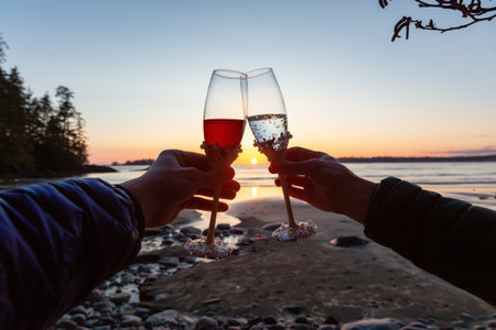 Man and Woman Cheers with Champagne Flute Glasses on the Beach at Sunset. Tofino, Vancouver Island, British Columbia, Canada.の写真素材